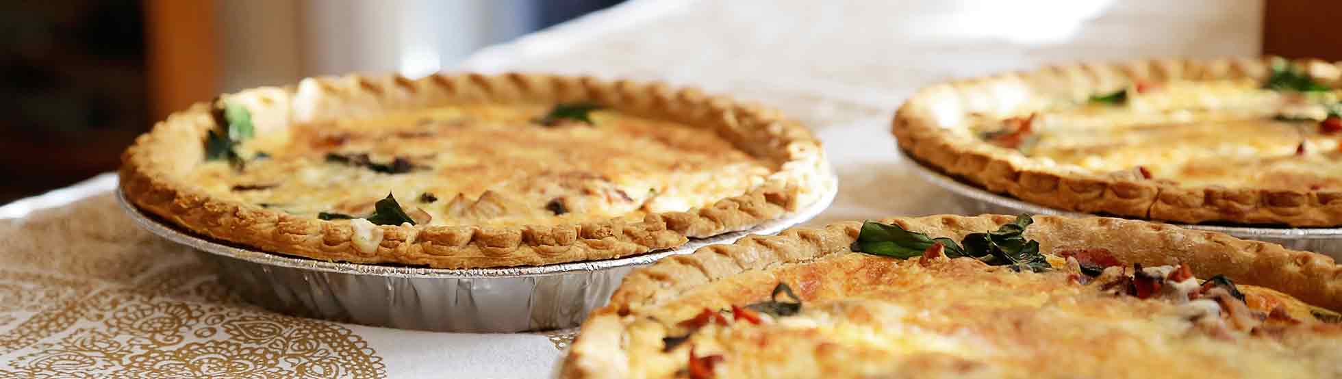 Three pies in foil containers rest on decorative cloth